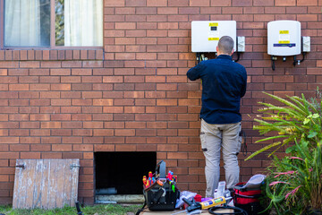 Electrical tradie working as an electrician doing a solar power installation on house