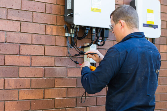 Electrician tradie using multimeter tool to check power in solar system installation
