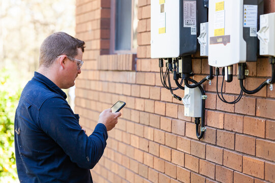 Electrician using mobile phone device to troubleshoot