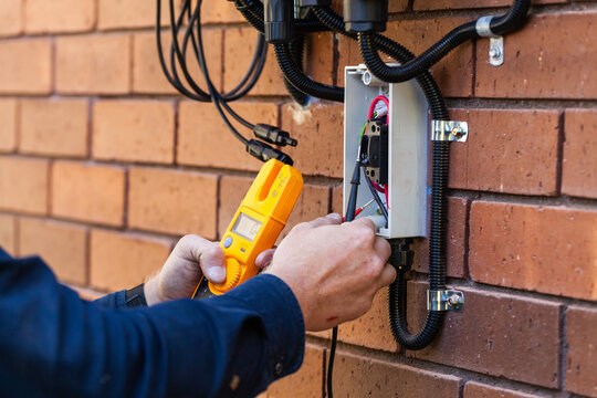 Electrician using multimeter tool to check power in solar system installation