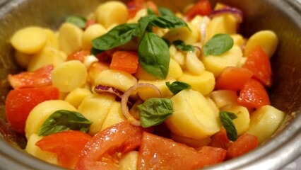 A bowl of fresh tomato salad, potatoes, Tropea onions and basil.