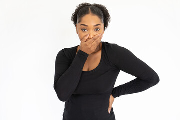 Portrait of frightened young woman covering mouth with hand in studio. African American lady wearing black longsleeve forgetting something or making mistake. Forgetfulness or fault concept