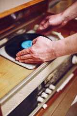 Istra, Russia - September 06, 2021: Vinyl record, spinning on turntable, Vintage record player with radio 60's. Mens hands putting vintage record in vinyl player