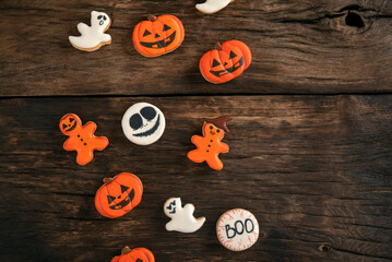 Ginger cookies for Halloween in the form of a pumpkin and ghosts on wooden table. Smiling cookie. Top view