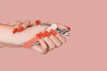 Female hand with red nail design. Mate red nail polish manicure. Female model hand hold manicure tools.