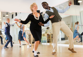 Lady learning to dance lindy hop with man in dance school