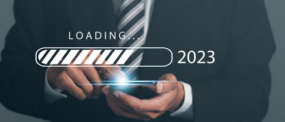 Businessman with mobile phone with virtual download bar with loading progress bar to new year 2023.