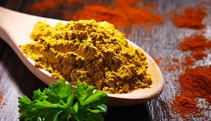 Wooden spoon with curry powder on kitchen table