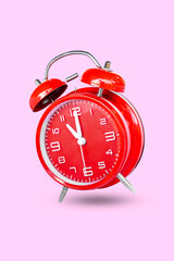 remote image of The red alarm clock is set to 11:00 a.m. a pink background.
