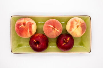 Peaches on green plate on a white background