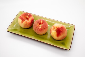 Peaches on green plate on a white background