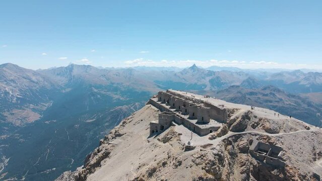 aerial scenic view of ruined artillery batteries with people (515a Batteria Guardia alla Frontiera), Mont Chaberton peak. Mont Rochebrune peak in background