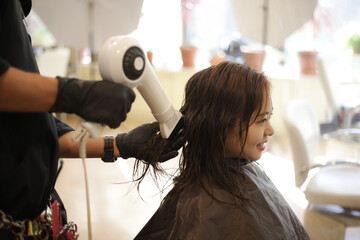 女性の髪にドライヤーをかける男性美容師