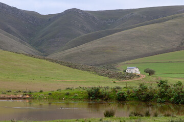 Farmhouse in the mountains with a pond in the foreground