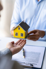 Real estate agents present and deliver samples of model homes after consulting with clients to decide whether to sign home insurance contracts about the mortgage and home insurance offers.