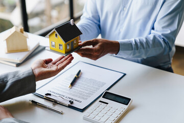 Real estate agents present and deliver samples of model homes after consulting with clients to decide whether to sign home insurance contracts about the mortgage and home insurance offers.