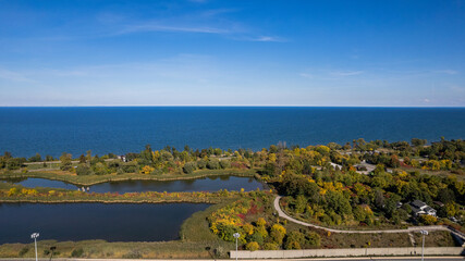 Aerial view of the blue sea and lakes with coastline trees and buildings under the blue sky