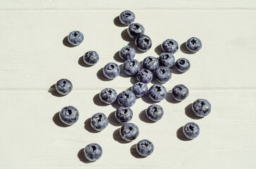 Fresh blueberry berries lie under the sunlight with shadows on a white wooden background. The topic of ecological, healthy and natural food, vegans