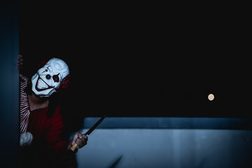 Asian handsome man wear clown mask with weapon at the night scene,Halloween festival concept,Horror...