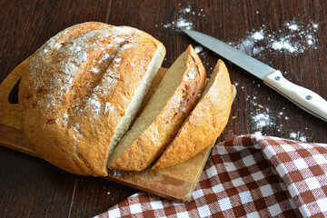 fresh bread with slices of bread on cutting board with knife 
