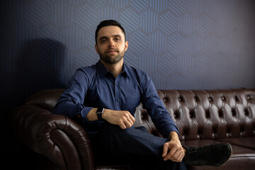 portrait man sitting on a sofa, man in business shirt in his office, young businessman in his living room