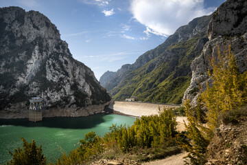 The water reservoir Lake Bovilla and the dam surrounded by mountains, blue sky, in Albania