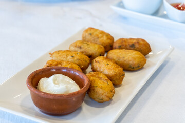 Cod croquettes with mayonnaise, on a white plate. Spanish tapas