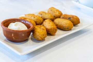 Cod croquettes with mayonnaise, on a white plate. Spanish tapas
