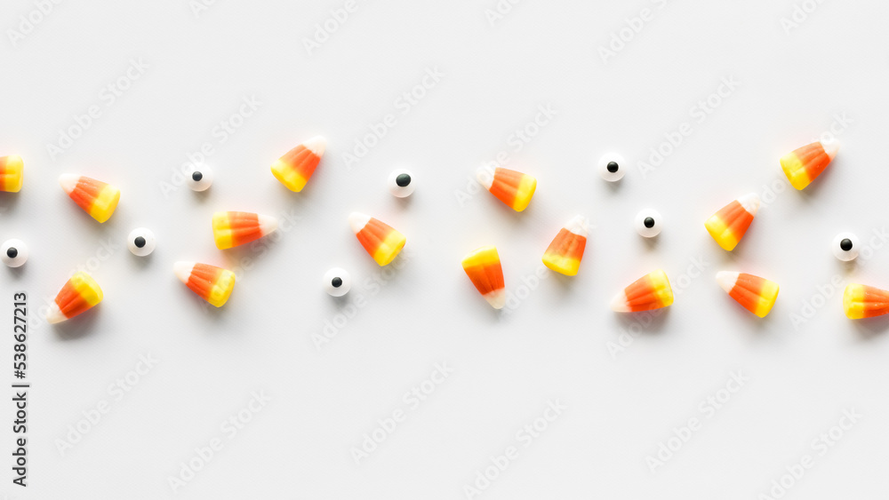 Wall mural A line of candy corn and candy eyeballs, against a white background.