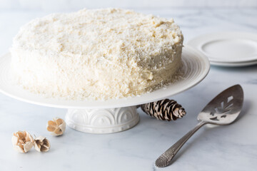A white frosted coconut covered cake surrounded by rustic decorations.