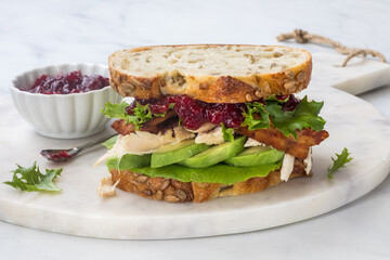 A homemade turkey and bacon club served with cranberry sauce.