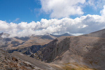 Trekking on mystical hiking trail leading to Mount Olympus (Mytikas, Skala, Stefani) in Mt Olympus National Park, Thessaly, Greece, Europe. Panoramic view of the cloud covered slopes and rocky ridges