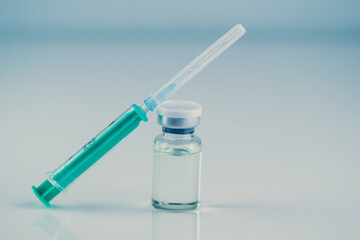 close up of glass medicine vial with syringe and needle isolated on white background. flu vaccine,...