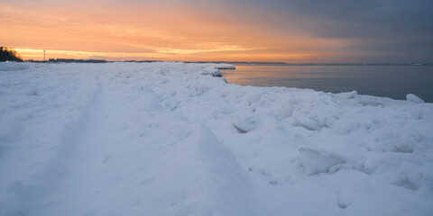 Fototapeta na wymiar orange sunset on the snowy seashore