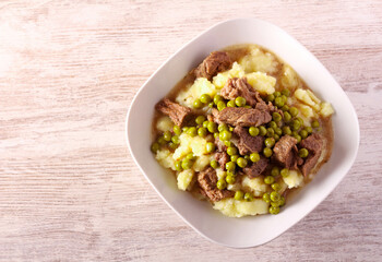 Mashed potatoes and beef stew with peas