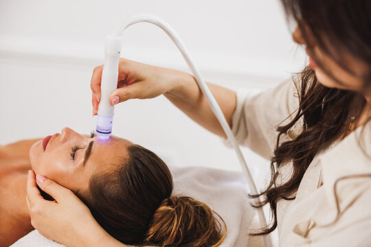 Beauty Therapist Performing Hydrafacial Procedure On Woman