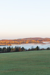 View of rolling hills and farmland with fall foliage and aspen forests in Aroostook county, Maine.