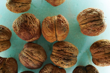 A group of large unshelled fresh walnuts on a blue background