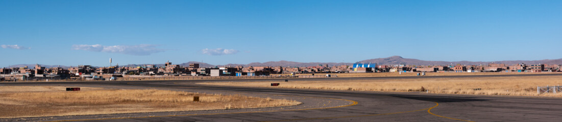 An Asphalt Road in the Middle of the Dry and Yellow Soil in Contrast to a Beautiful Clear Blue Sky with Mountains in the Distance - obrazy, fototapety, plakaty