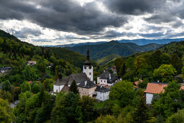 Fototapeta na wymiar view of the village and Roman Catholic church in Spania Dolina with green summer forest