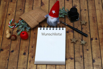 Wunschliste mit Nikolaus und Weihnachtsdekoration auf Holzhintergrund.