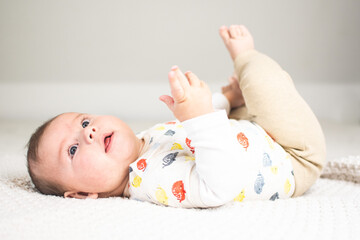 baby 5 months old lying on back feet in air