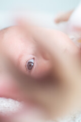 Fototapeta premium portrait baby looking through hand, focus on eye