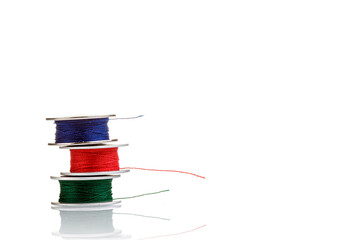 spools of thread in blue, red, green colors on a white background