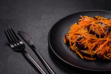Korean salad with eggplant, carrots, garlic, spices and herbs on a dark concrete background