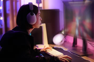 Fotobehang Gaming Young Asian Pretty Pro Gamer win in Online Video Game. young playing game online at home. Gamer controlling joystick for video game. Teenage girls leisure game in neon light room at home  © Thitiporn
