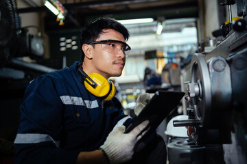 Technicians, workers, Asian engineers wear safety controls operating grinding lathes working in industrial plants. Engineers work at the factory.