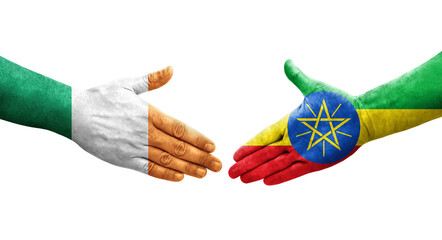 Obraz premium Handshake between Ethiopia and Ireland flags painted on hands, isolated transparent image.