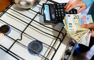 The family calculates gas bills, utility bills. Euro and dollar bills lie near a burning gas burner. The concept of increasing the cost of natural gas supply and payment. Energy crisis. 