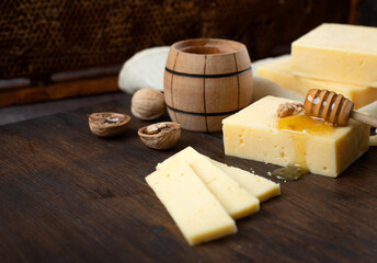 Hard cheese on a dark background. Cheese with honey and nuts.